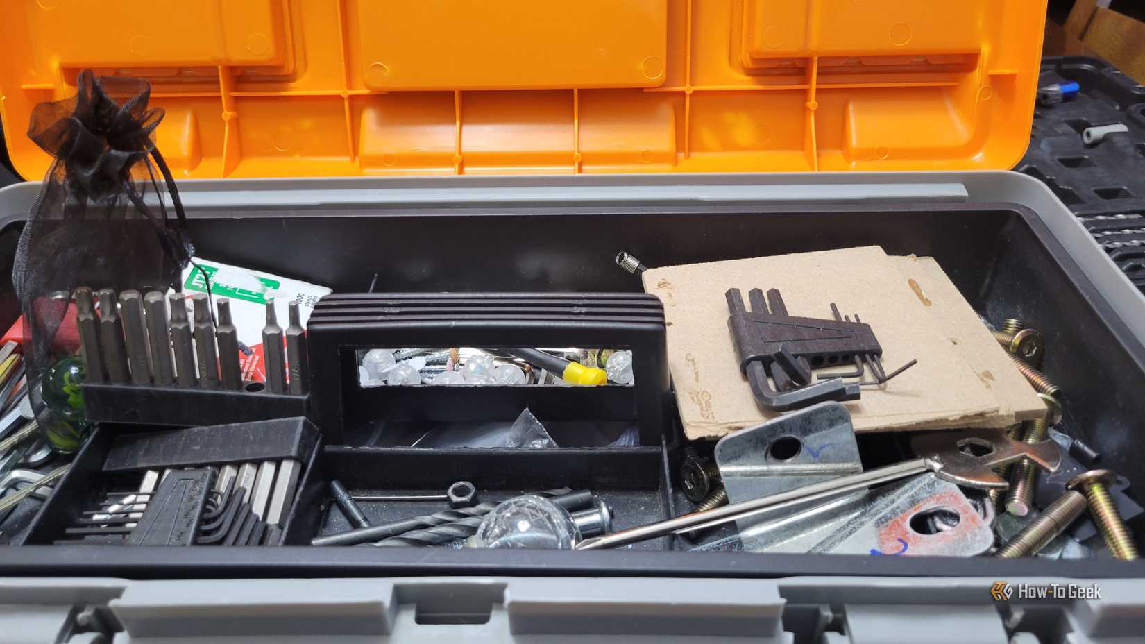 A close of up of a tool box with a bunch of bits and tools in it near a bit case.