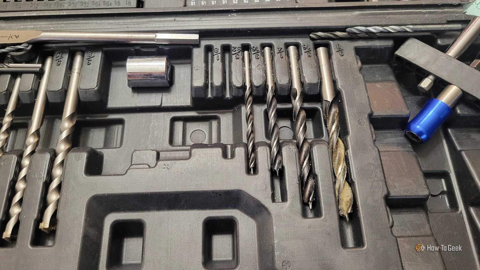 A close up of used drills in a case that holds drill bits.