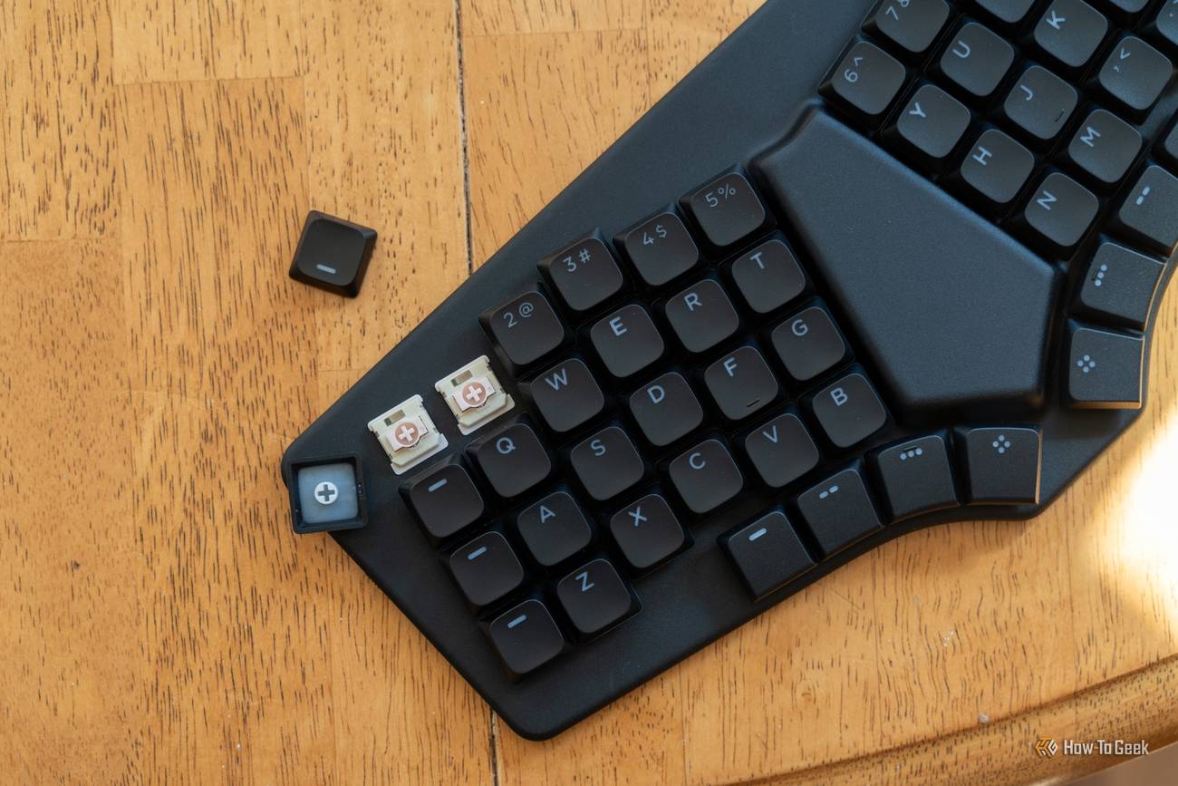 Dygma Sonsei with two keycaps pulled to show its hot-swappable Gateron Strawberry Chocolate switches, with a loose keycap beside it.