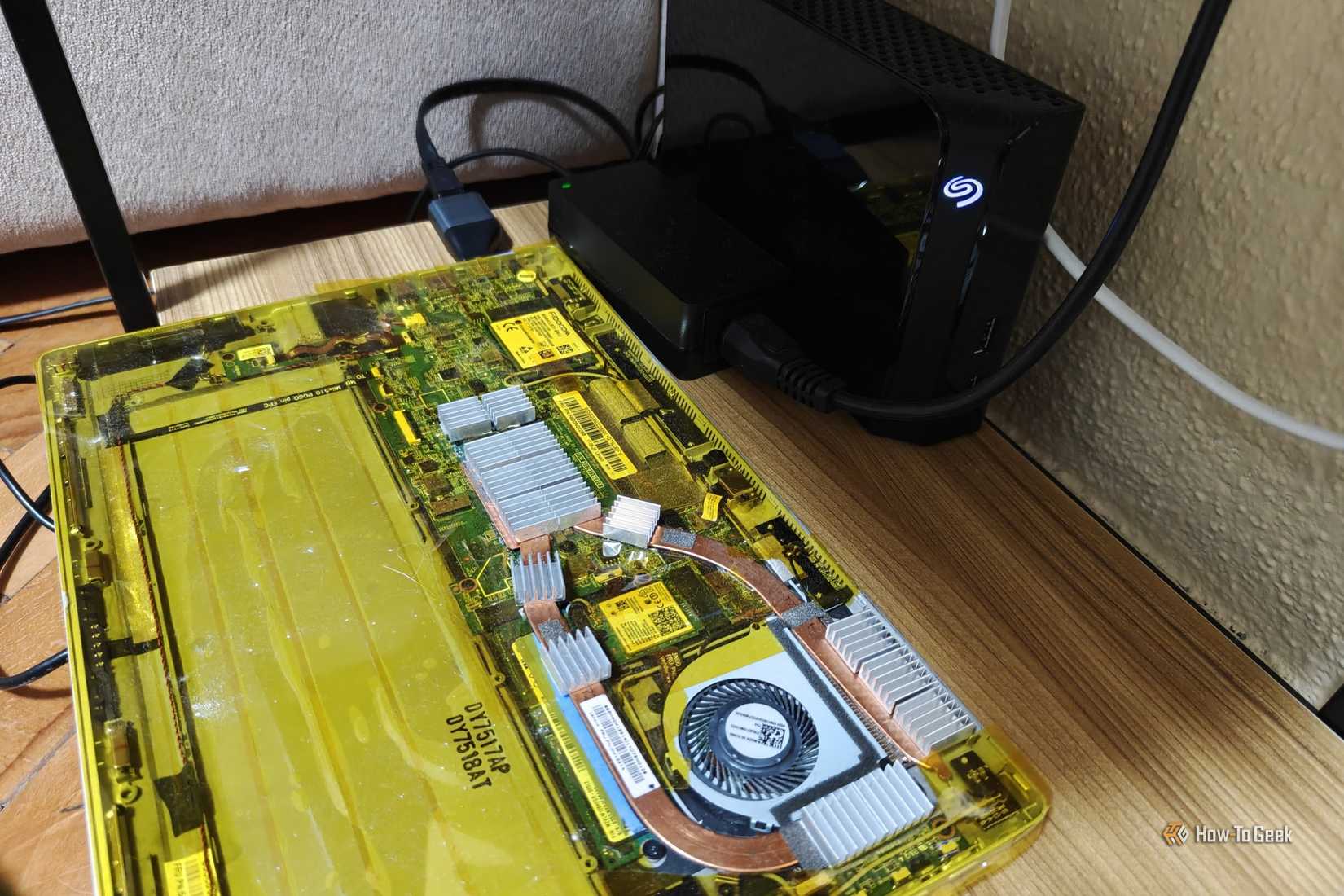 A laptop that's being used as a home server with an external hard drive next to it and an Ethernet adapter plugged in.