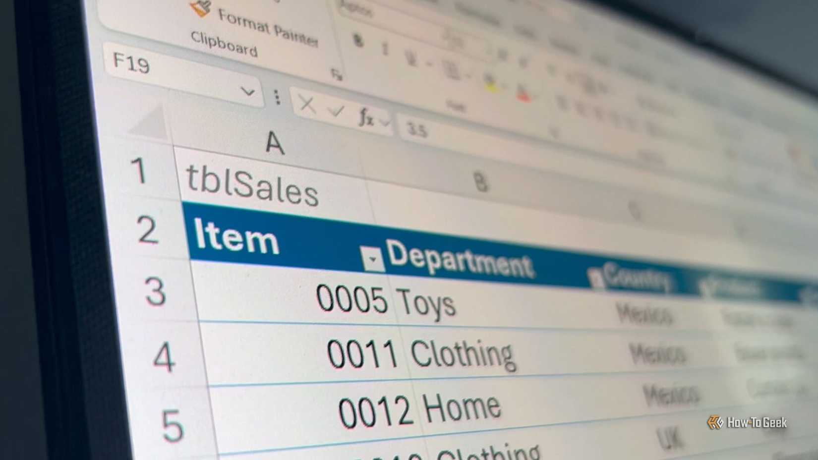 A computer monitor displays a Microsoft Excel worksheet with tblSales written in cell A1 above an inventory table.