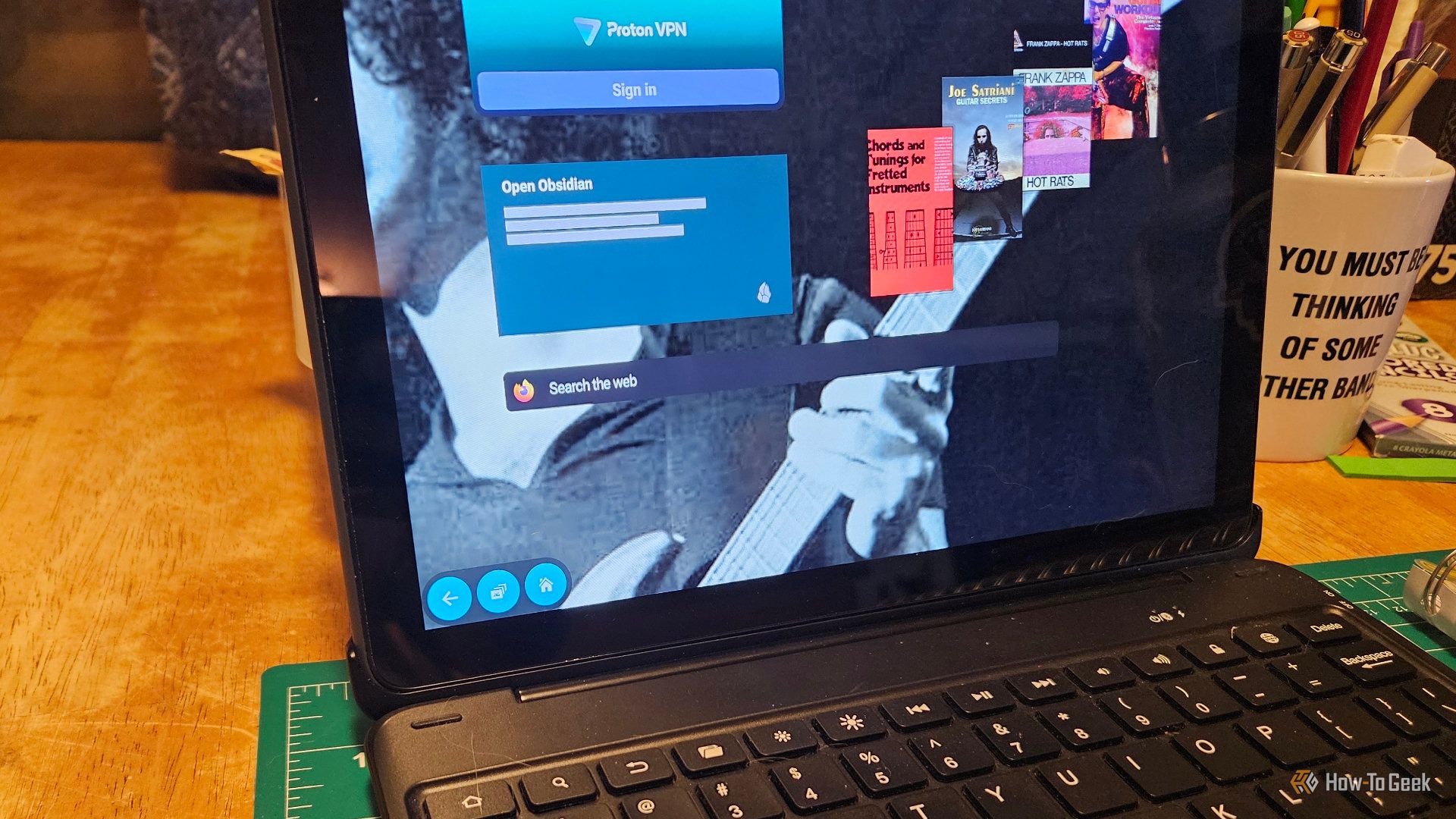 A Fire tablet with a keyboard showing a bunch of widgets on a screen with Frank Zappa wallpaper.