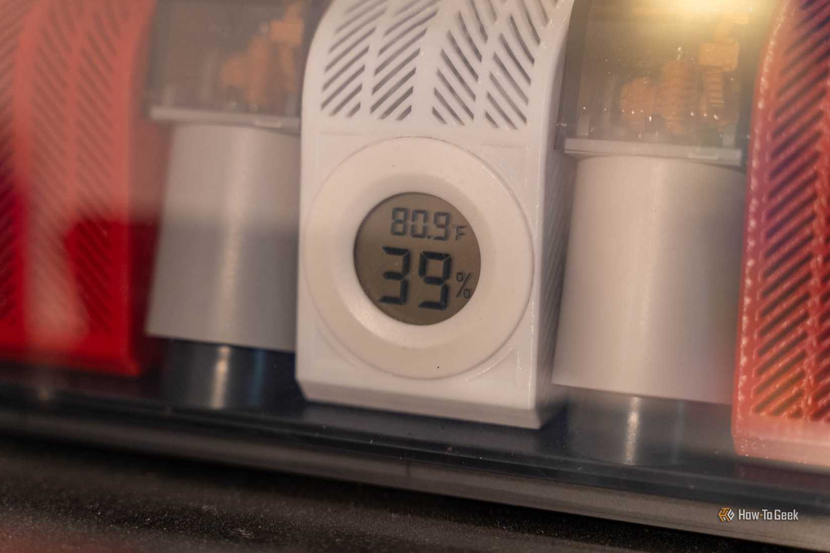 Mini hygrometer reading 39% humidity and 80.9°F in a 3D-printed holder inside a Bambu Lab AMS.