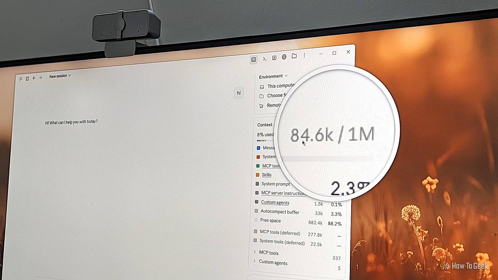 Monitor photo of the Claude desktop app with a magnified callout on 84.6K of 1M tokens used after saying hi.