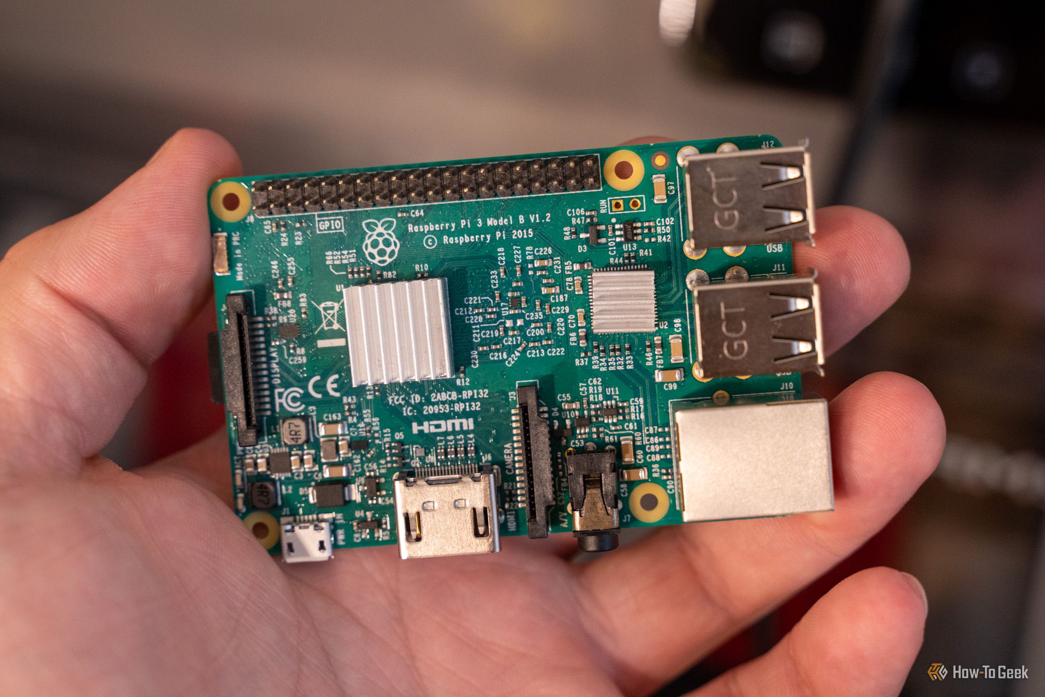 Raspberry Pi 3 Model B held in a hand, showing two silver heatsinks and its connectors.
