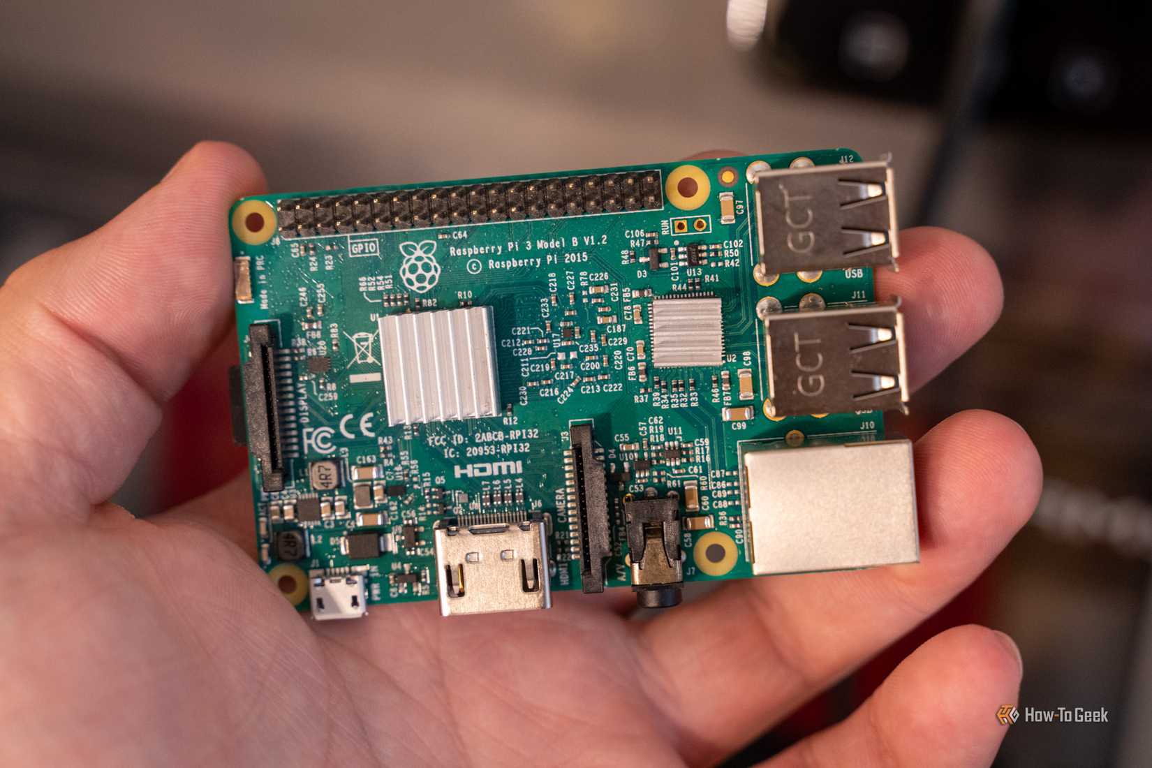 Raspberry Pi 3 Model B held in a hand, showing two silver heatsinks and its connectors.