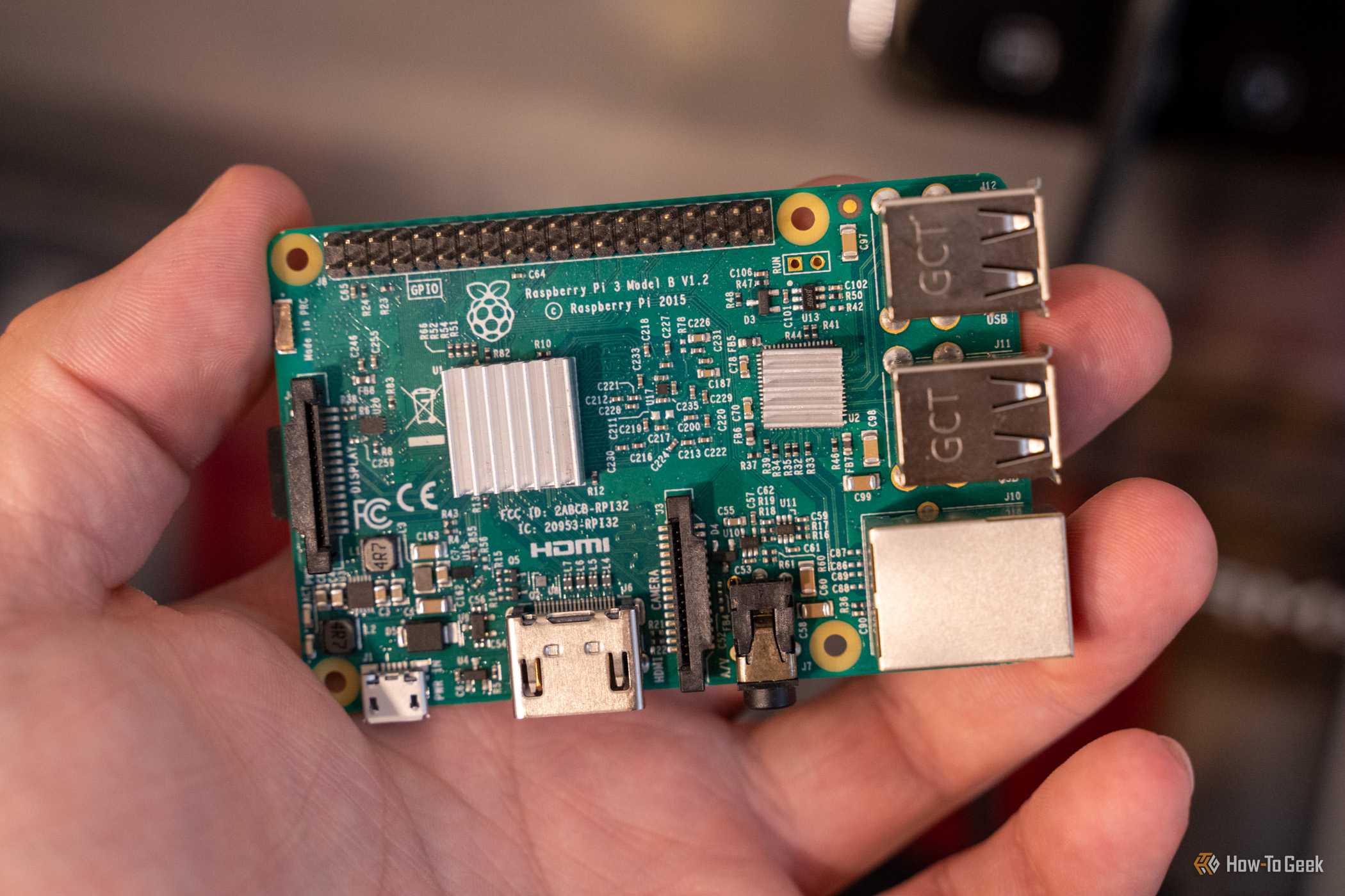 Raspberry Pi 3 Model B held in a hand, showing two silver heatsinks and its connectors.