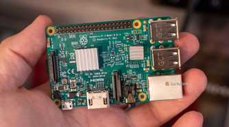 Raspberry Pi 3 Model B held in a hand, showing two silver heatsinks and its connectors.