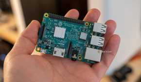 Raspberry Pi 3 Model B resting diagonally on an open palm, with its USB and Ethernet connectors visible.