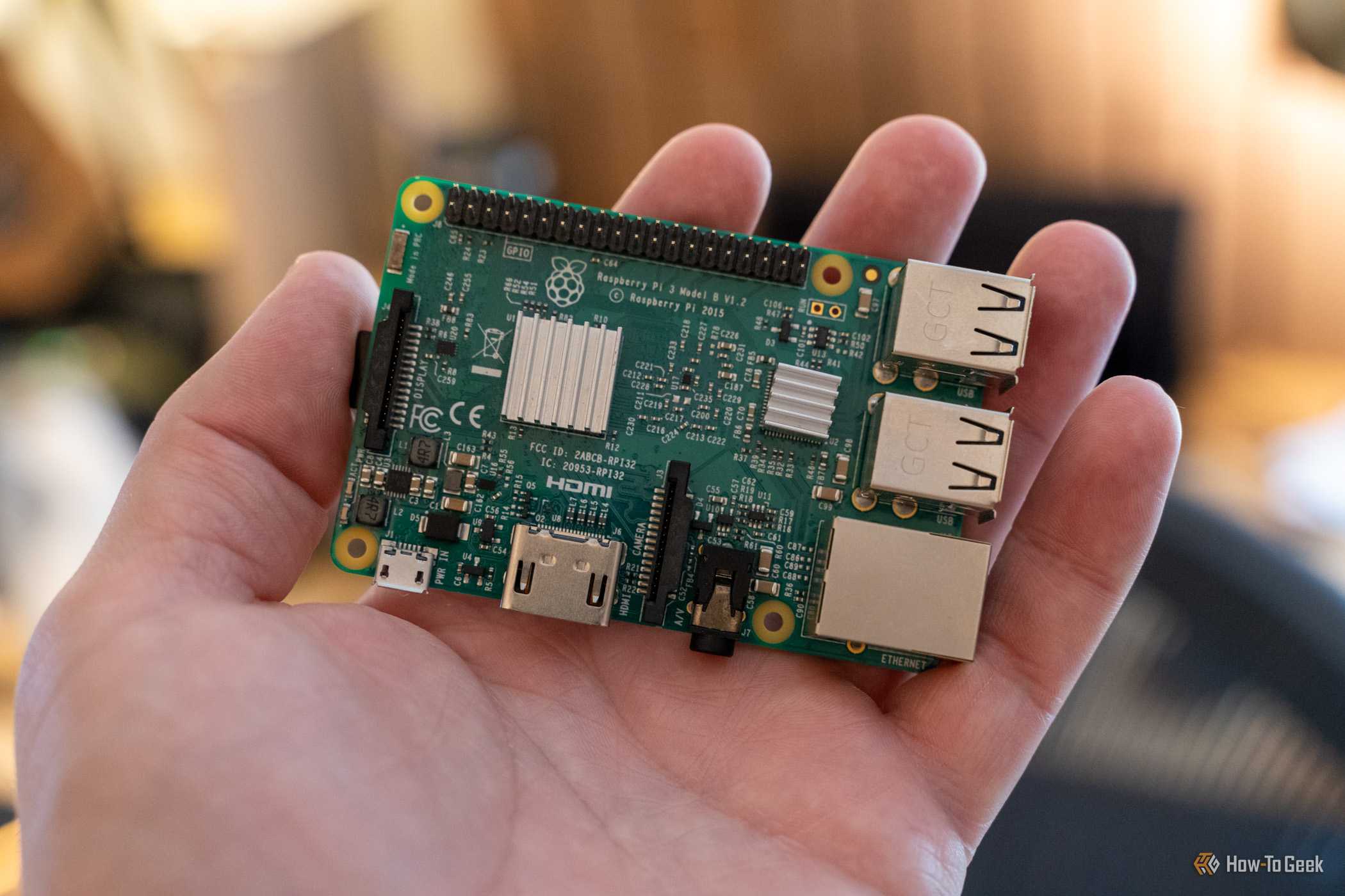 Top view of a Raspberry Pi 3 Model B on an open palm, showing its heatsinks, GPIO header, and ports.