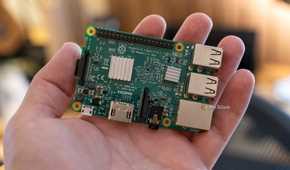 Top view of a Raspberry Pi 3 Model B on an open palm, showing its heatsinks, GPIO header, and ports.