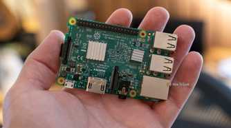Top view of a Raspberry Pi 3 Model B on an open palm, showing its heatsinks, GPIO header, and ports.