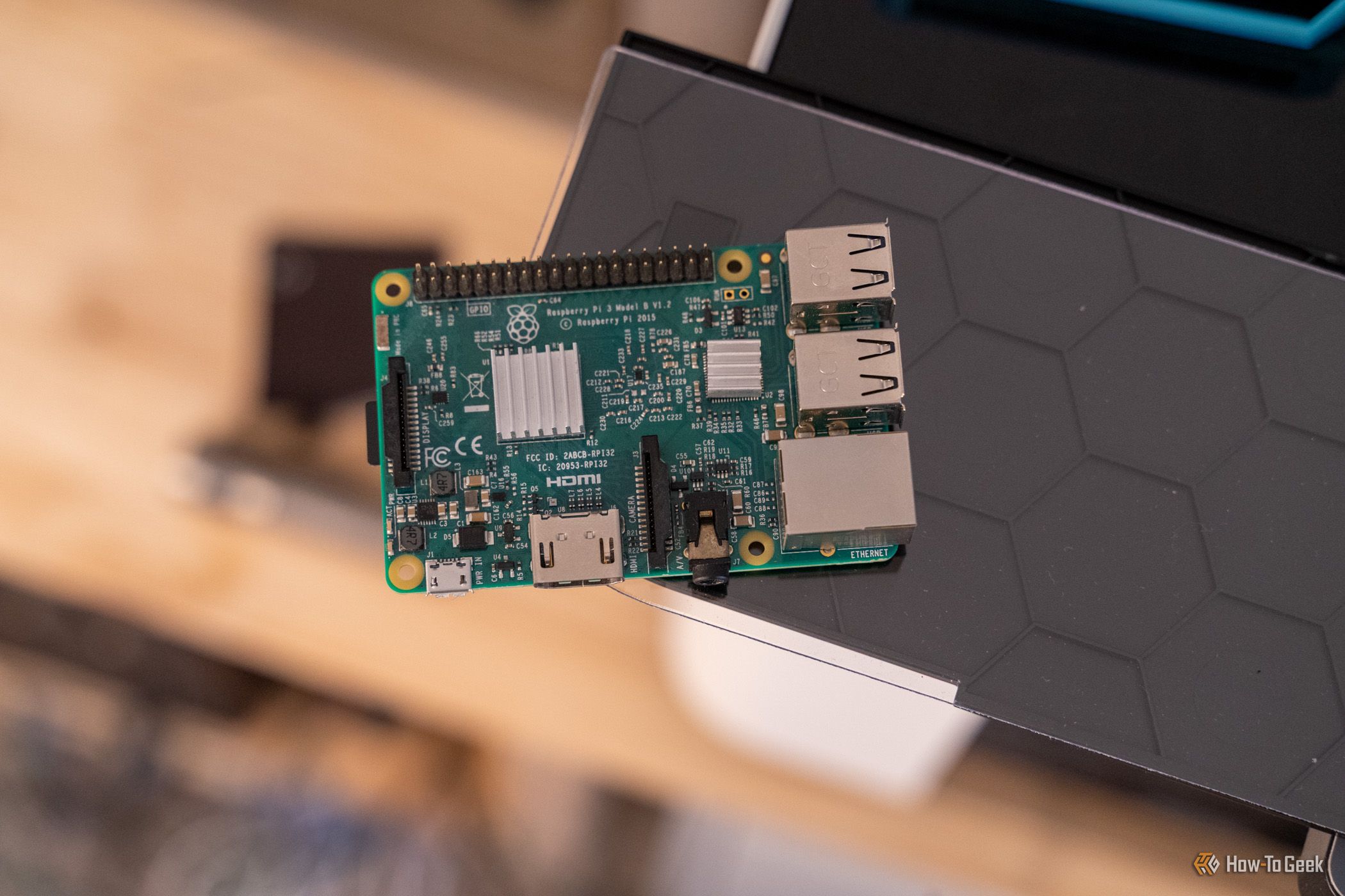 Raspberry Pi 3 Model B resting on a black shelf with its heatsinks and ports visible.