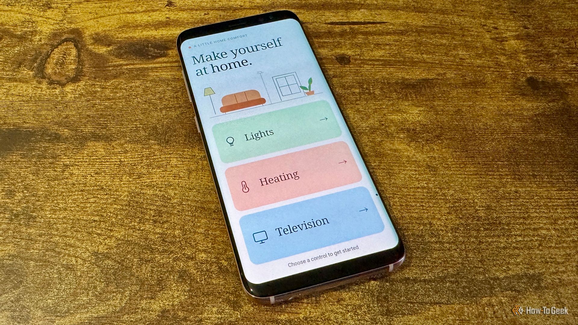 Samsung phone angled on a wooden table showing the guest remote main screen with Lights Heating and Television buttons.