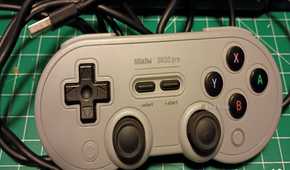A gray USB 8bitDo controller on a green mat.