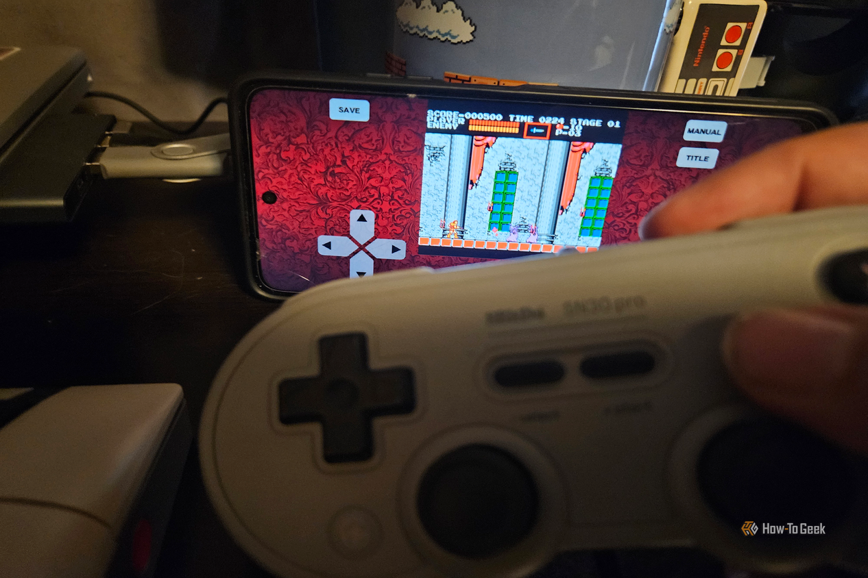 A hand holds a gray 8BitDo controller while playing a Castlevania on an Android screen.
