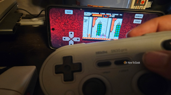 A hand holds a gray 8BitDo controller while playing a Castlevania on an Android screen.