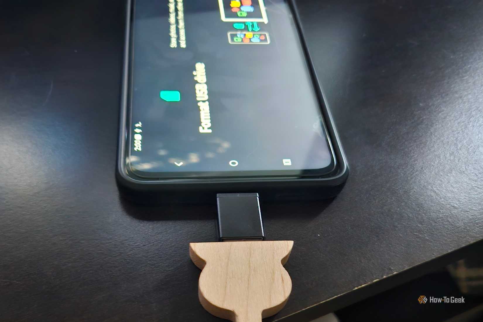 A wooden USB drive plugs into a Motrola phone displaying a formatting screen.