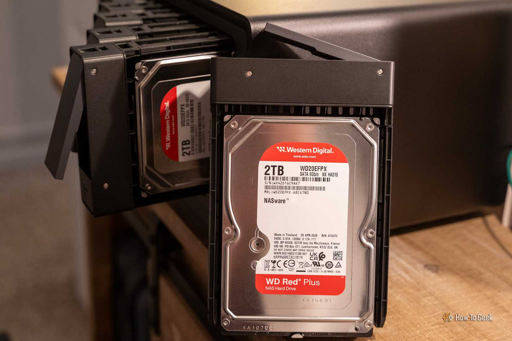 A 2TB WD Red Plus hard drive in a removed tray in front of the Ugreen DXP8800 Ultra.